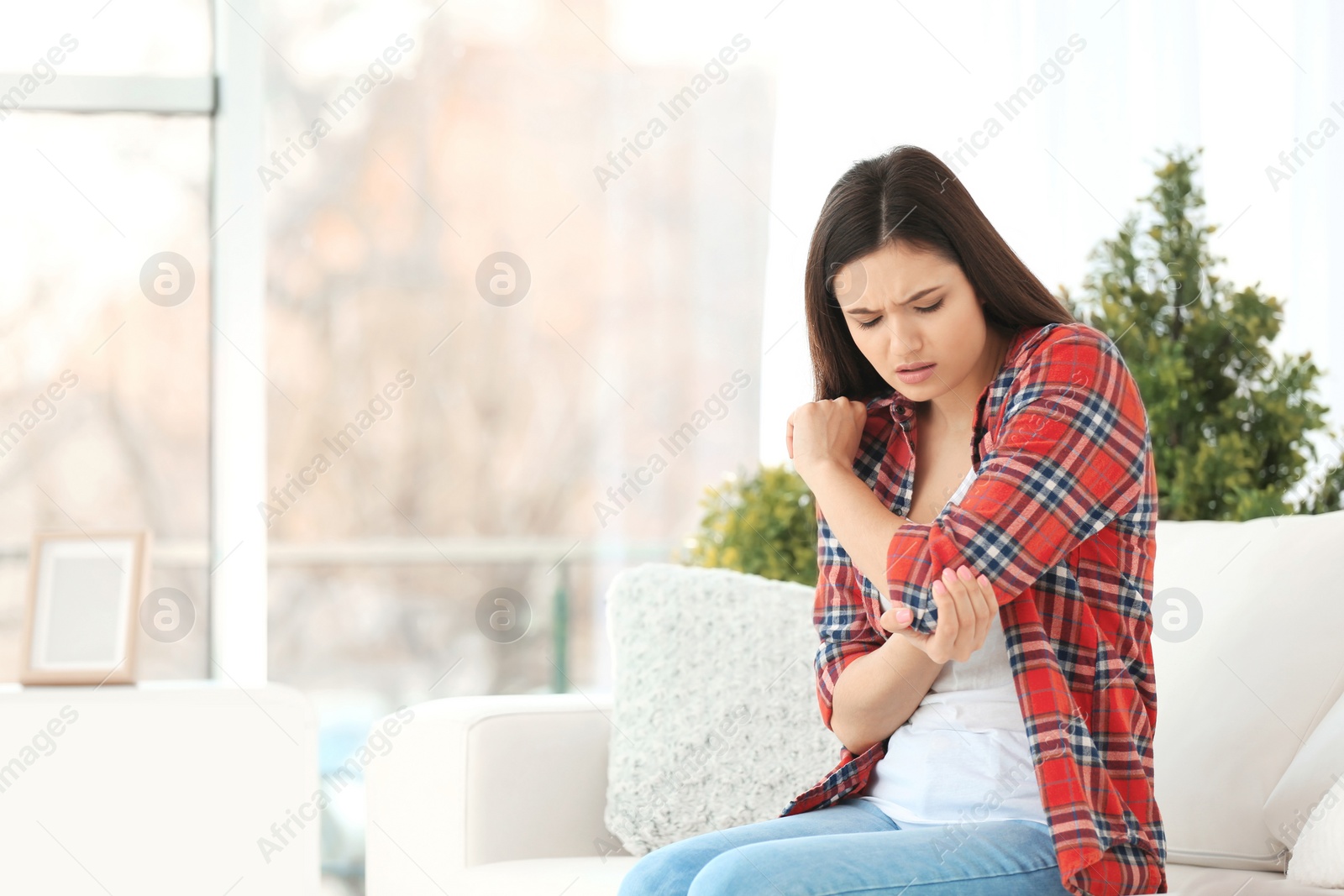 Photo of Young woman suffering from elbow pain  at home