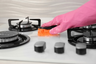 Photo of Person cleaning gas stove with sponge, closeup