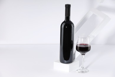 Photo of Stylish presentation of delicious red wine in bottle and glass on white background. Space for text