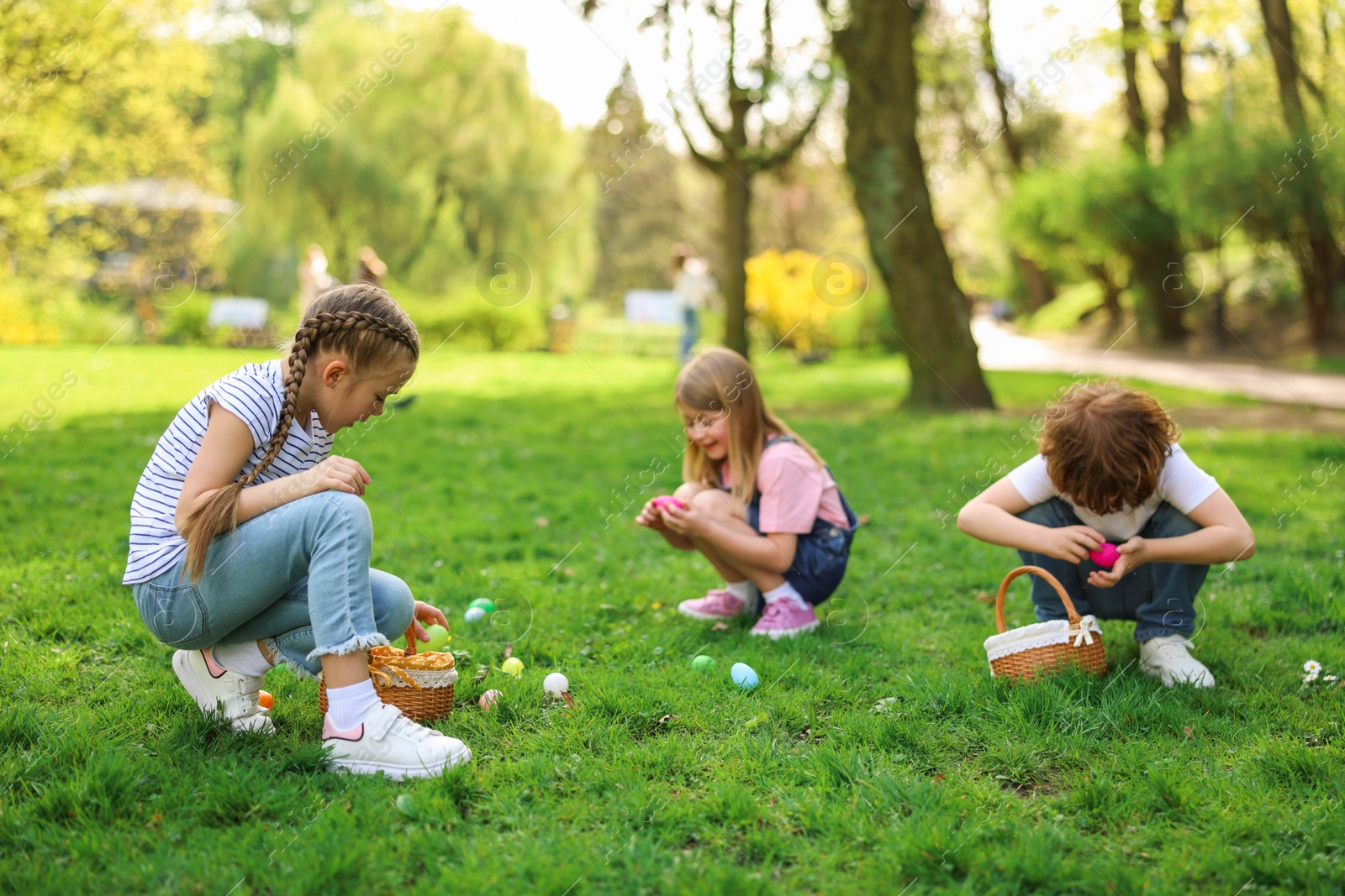 Photo of Easter celebration. Cute little children hunting eggs outdoors