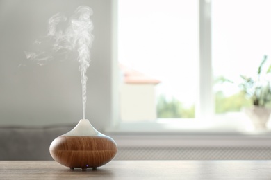 Photo of Modern aroma lamp on table against blurred background with space for text