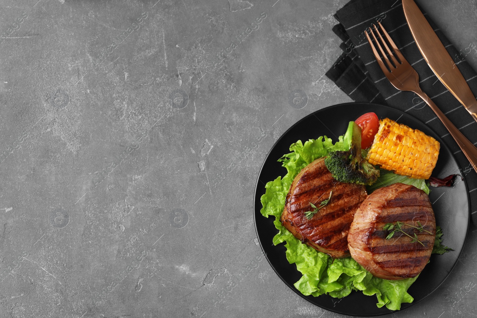 Photo of Delicious beef medallions served on grey table, flat lay. Space for text