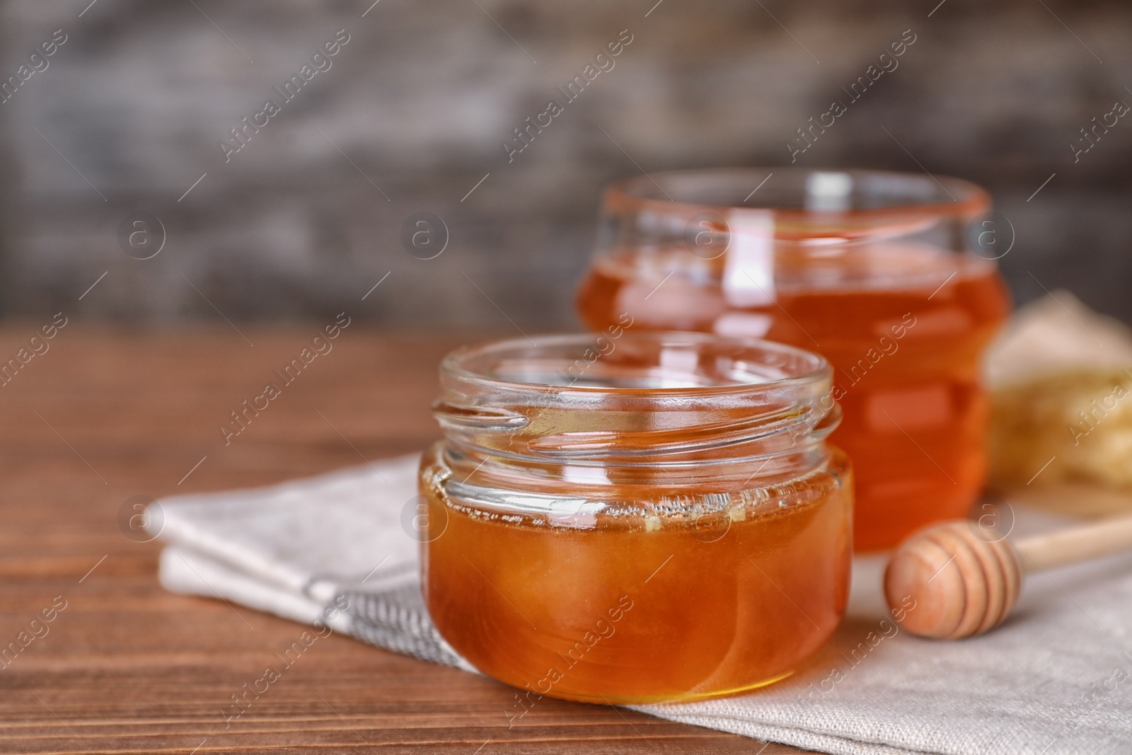 Photo of Glass jar with sweet honey and dipper on table, closeup