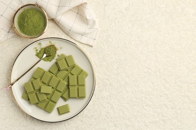 Photo of Pieces of tasty matcha chocolate bar and powder on white textured table, flat lay. Space for text