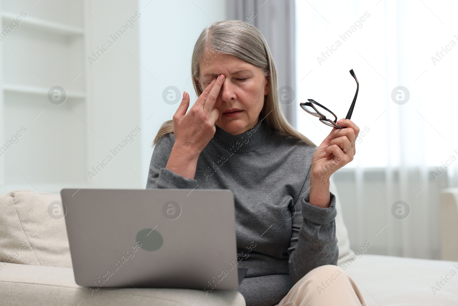 Photo of Overwhelmed woman with laptop sitting on sofa at home