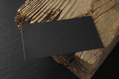 Photo of Empty business card and piece of wood on black background. Mockup for design