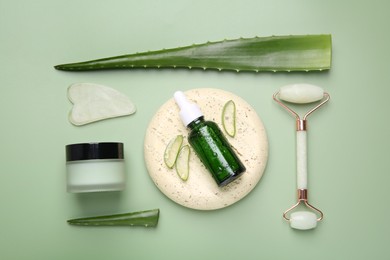 Photo of Flat lay composition with cosmetic products and cut aloe leaves on pale green background