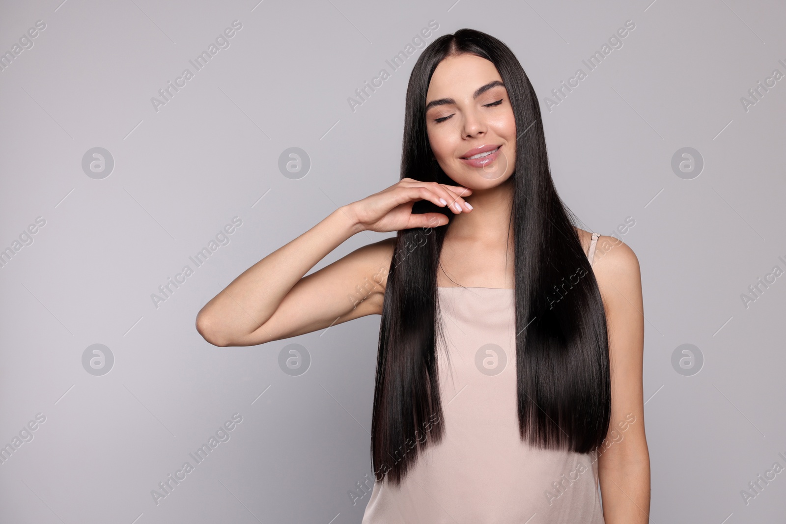 Photo of Portrait of beautiful young woman with healthy strong hair on light grey background, space for text