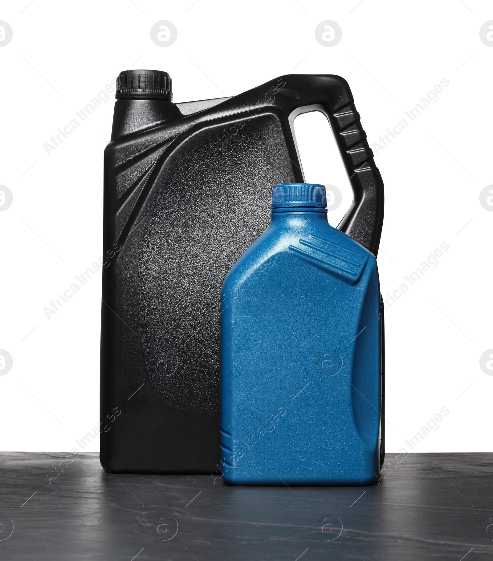 Photo of Motor oil in different canisters on black table against white background