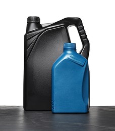 Photo of Motor oil in different canisters on black table against white background