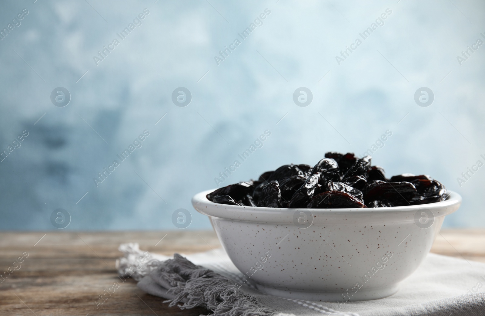 Photo of Bowl of sweet dried plums on table, space for text. Healthy fruit