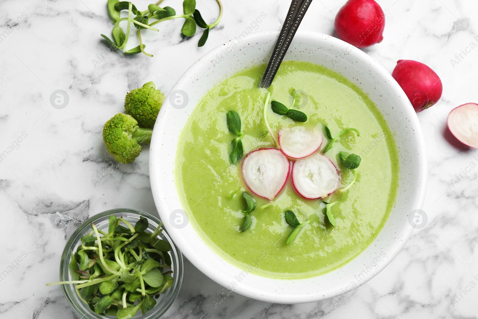 Photo of Flat lay composition with bowl of broccoli cream soup on white marble table