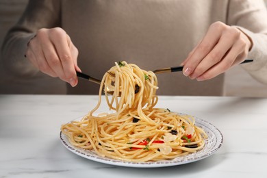 Woman eating delicious pasta at white marble table, closeup