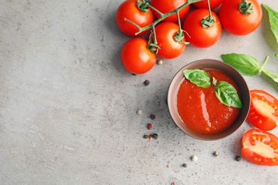 Photo of Flat lay composition with bowl of sauce and tomatoes on grey table. Space for text