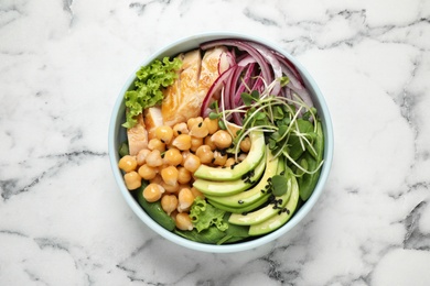 Delicious avocado salad with chickpea on white marble table, top view