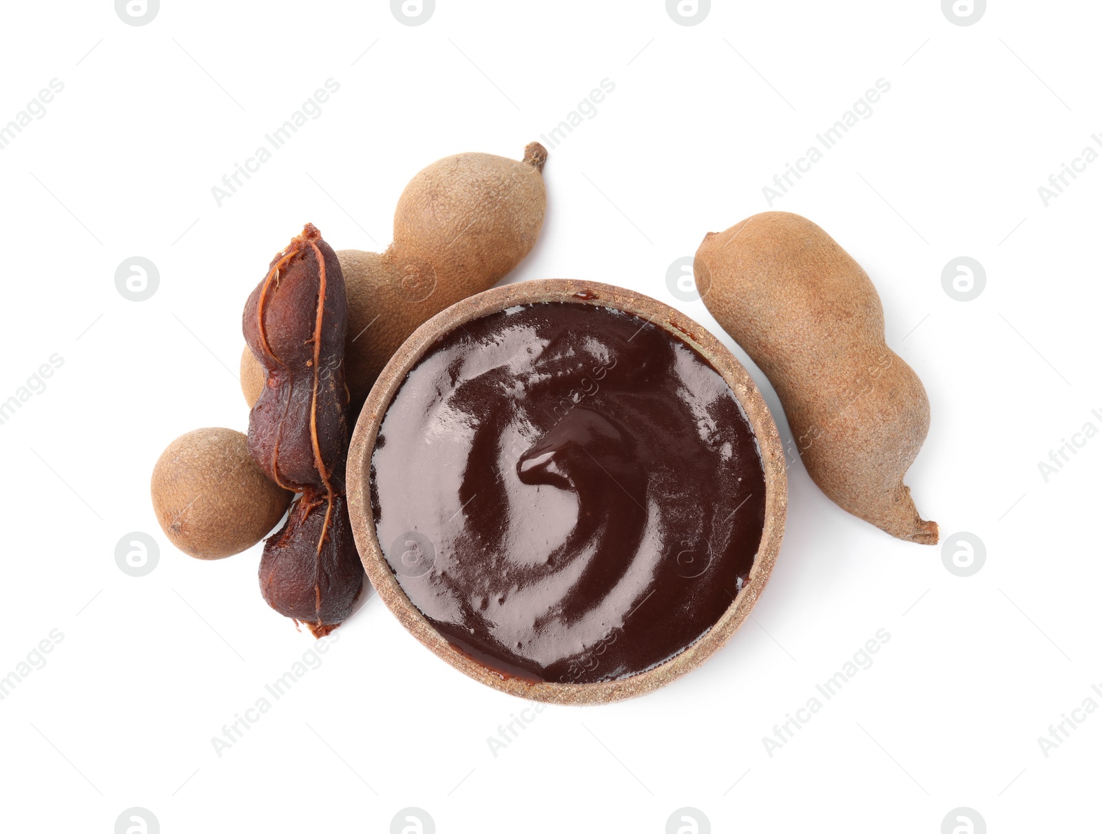 Bowl of tamarind sauce and fresh pods isolated on white, top view Photo of Bowl of tamarind sauce and fresh pods isolated on white, top view