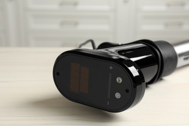 Photo of Thermal immersion circulator on white table in kitchen, closeup with space for text. Sous vide cooking
