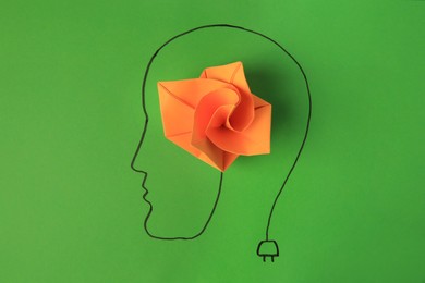 Photo of Drawn human head with orange paper flower as solution idea on green background, top view