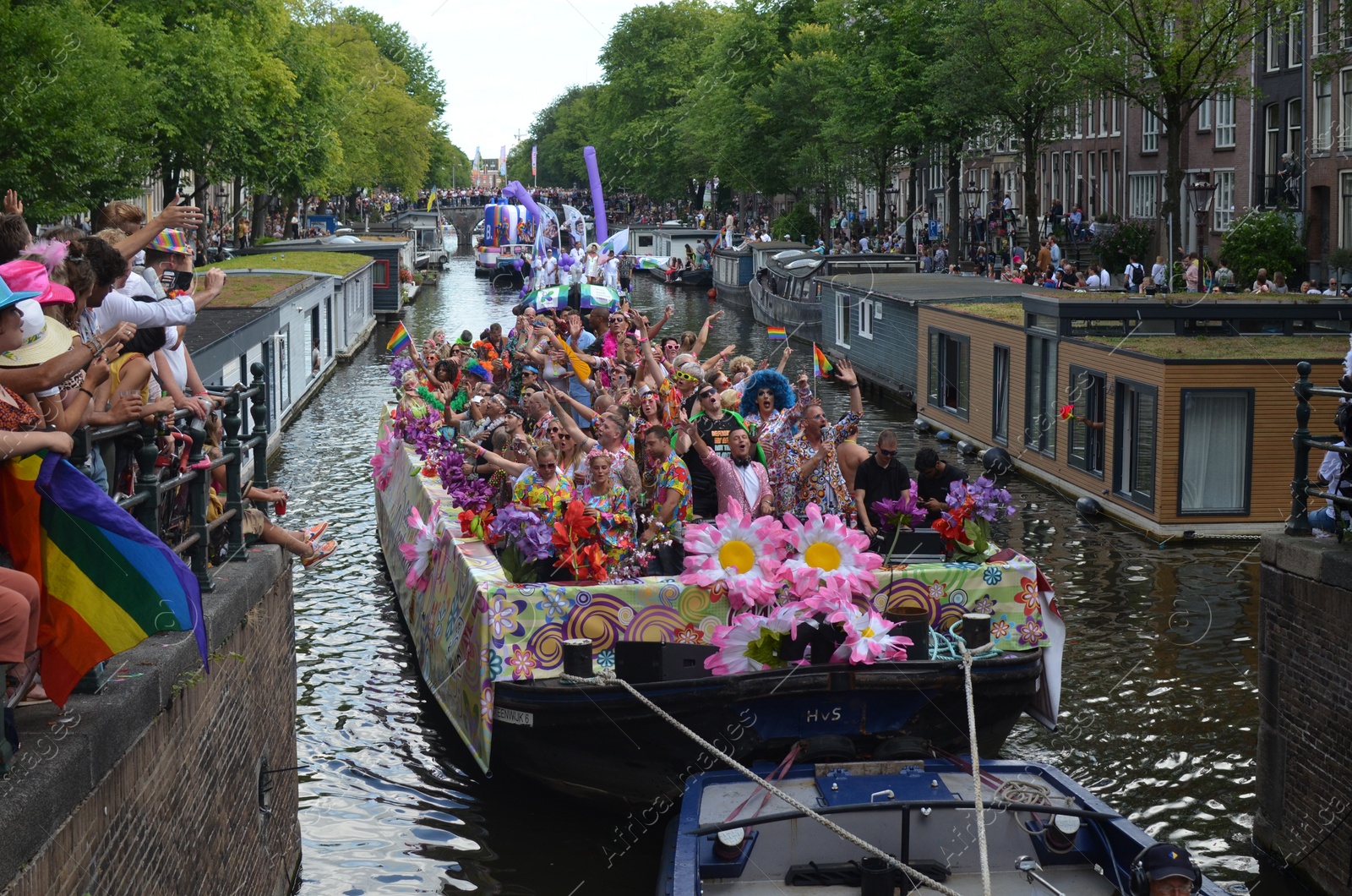 Photo of AMSTERDAM, NETHERLANDS - AUGUST 06, 2022: Many people in boats at LGBT pride parade on river