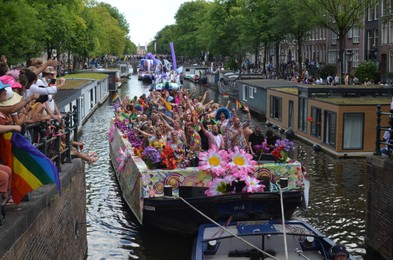 AMSTERDAM, NETHERLANDS - AUGUST 06, 2022: Many people in boats at LGBT pride parade on river