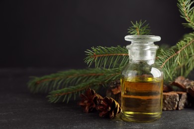 Pine essential oil, cones and branches on black table, closeup. Space for text