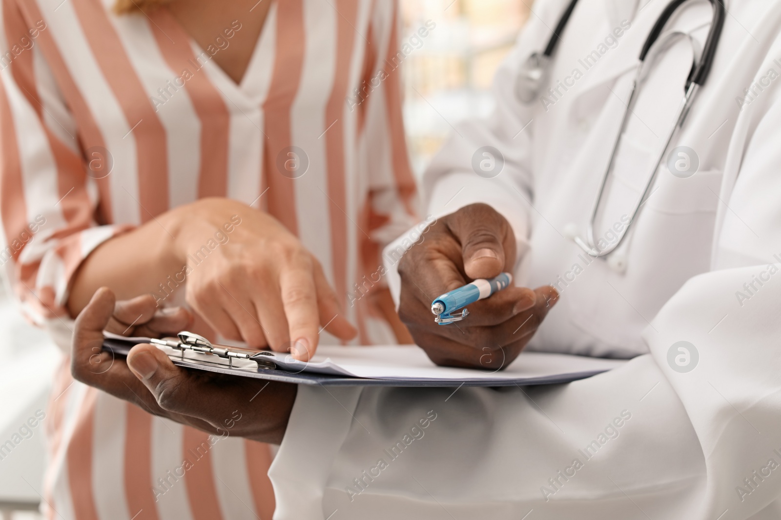 Photo of Young African-American doctor consulting patient in hospital