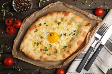 Fresh delicious Adjarian khachapuri served on wooden table, flat lay