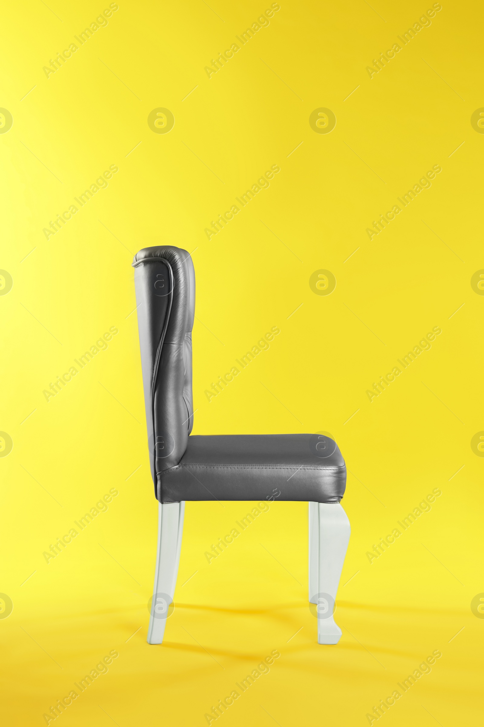 Photo of Stylish silver chair on yellow background. Element of interior design