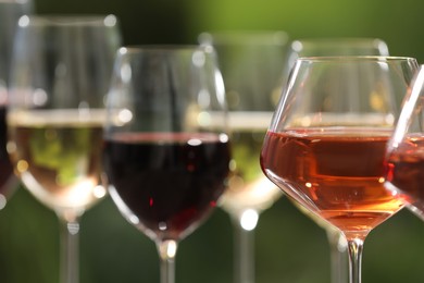 Different tasty wines in glasses against blurred background, closeup