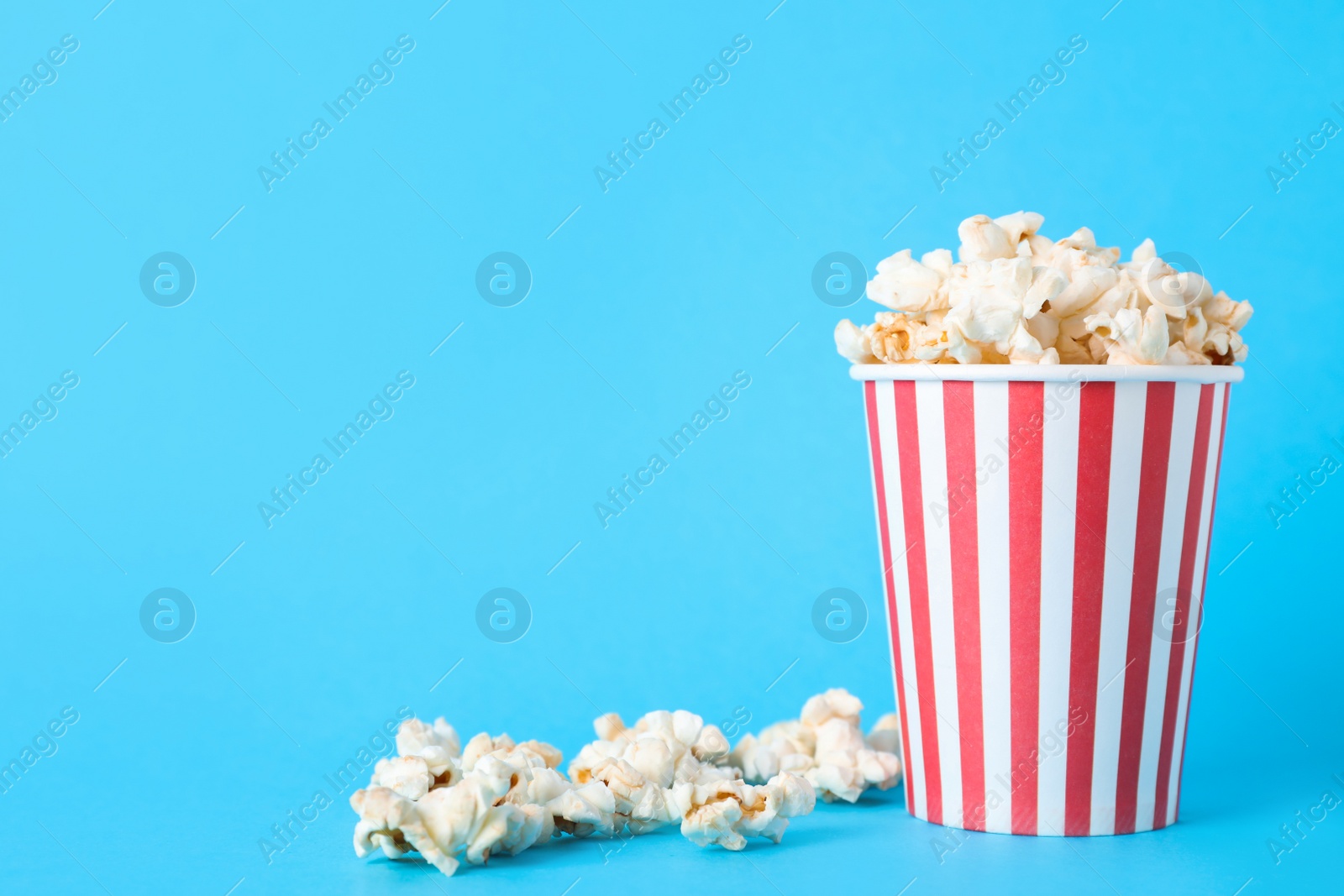 Photo of Delicious popcorn on light blue background. Space for text