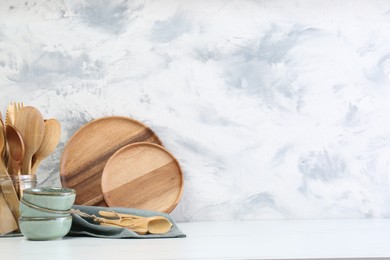 Photo of Different dishware and utensils on white marble table against textured wall. Space for text