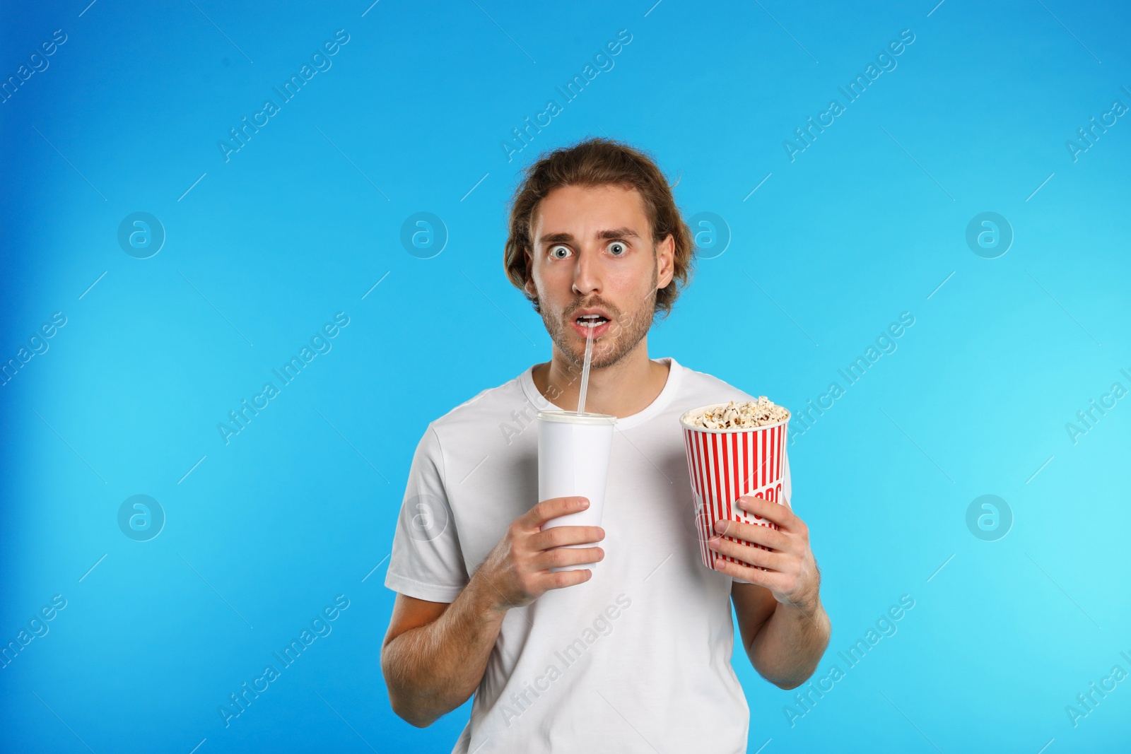 Photo of Emotional man with popcorn and beverage during cinema show on color background