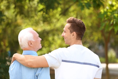 Photo of Man with elderly father outdoors on sunny day