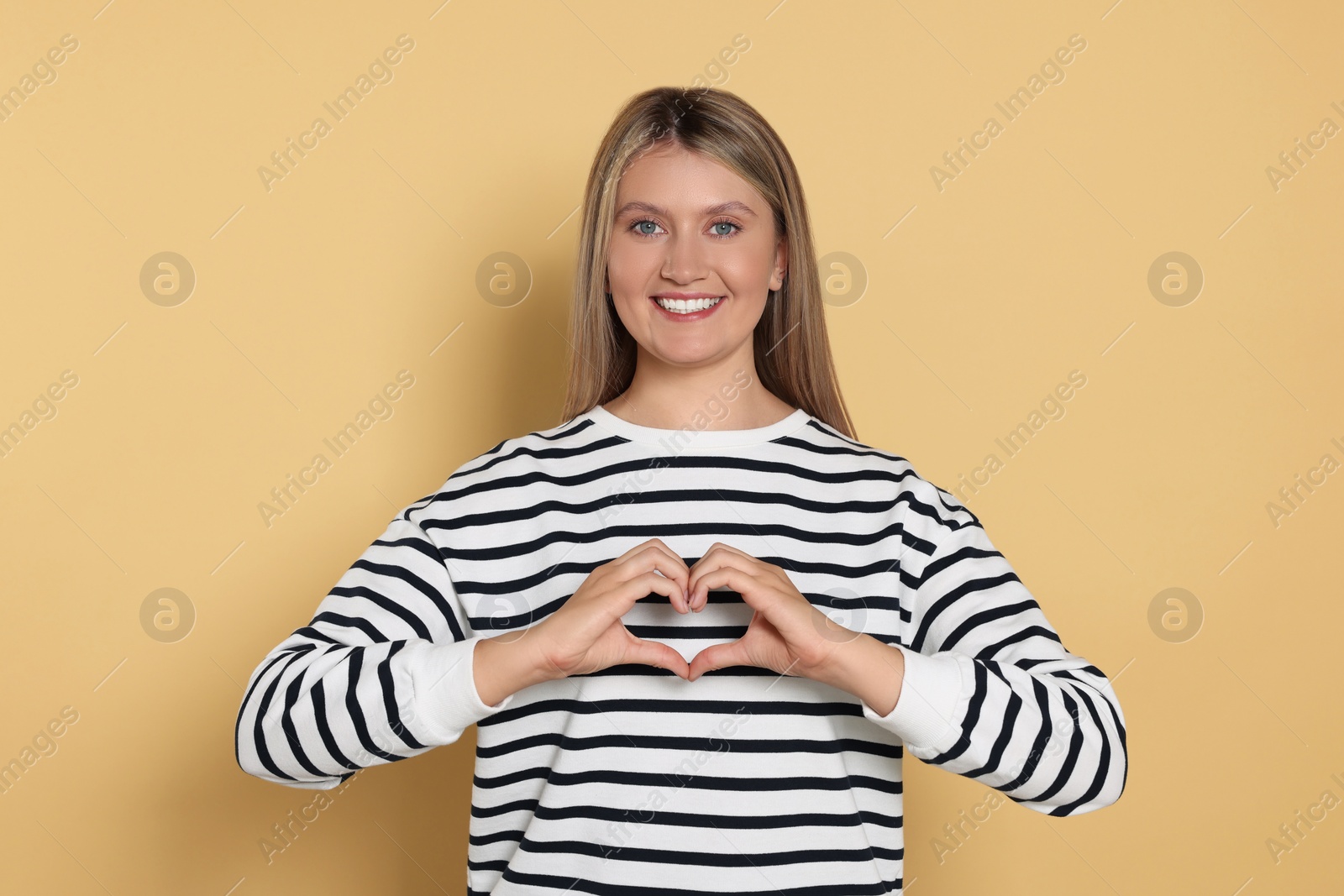 Photo of Happy volunteer making heart with her hands on beige background