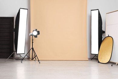 Photo of Beige photo background and professional lighting equipment in studio