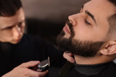 Photo of Professional hairdresser working with client in barbershop, closeup