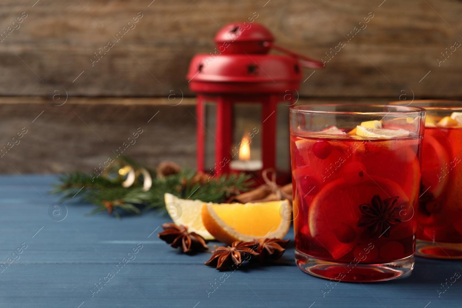 Photo of Delicious punch drink with cranberries and orange on blue wooden table. Space for text