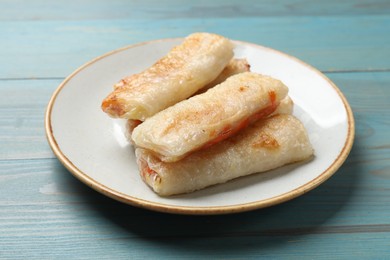 Photo of Delicious fried spring rolls on light blue wooden table, closeup