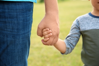 Man holding hands with his child outdoors, closeup. Happy family