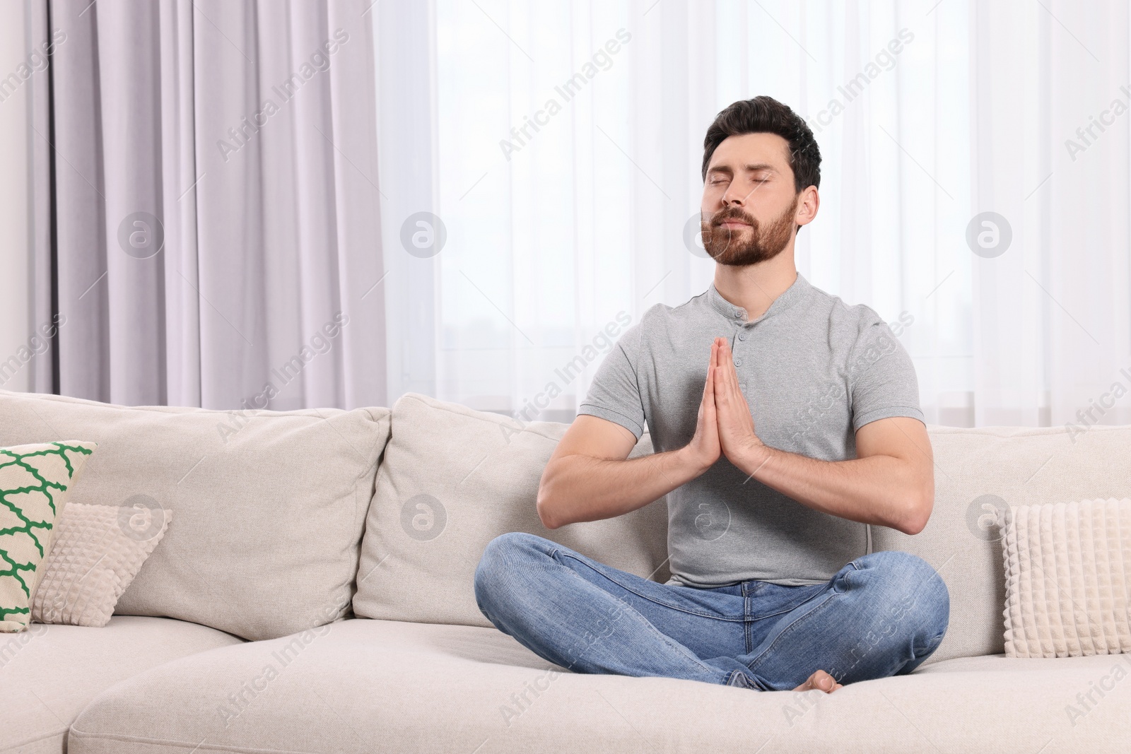 Photo of Man meditating on sofa at home, space for text
