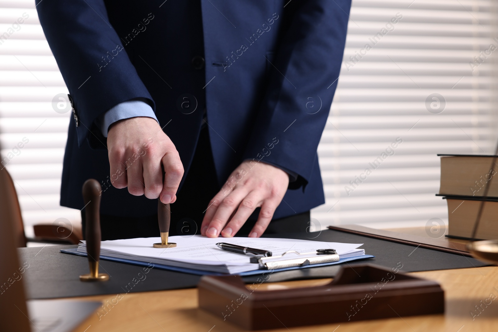 Photo of Notary stamping document at table in office, closeup