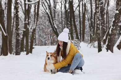 Woman with adorable Pembroke Welsh Corgi dog in snowy park