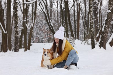 Photo of Woman with adorable Pembroke Welsh Corgi dog in snowy park