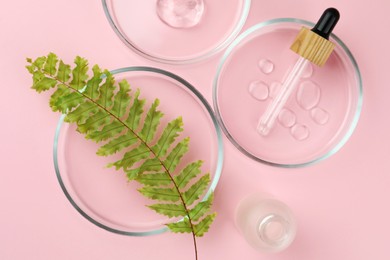 Photo of Petri dishes with fern leaf and cosmetic products on pink background, flat lay