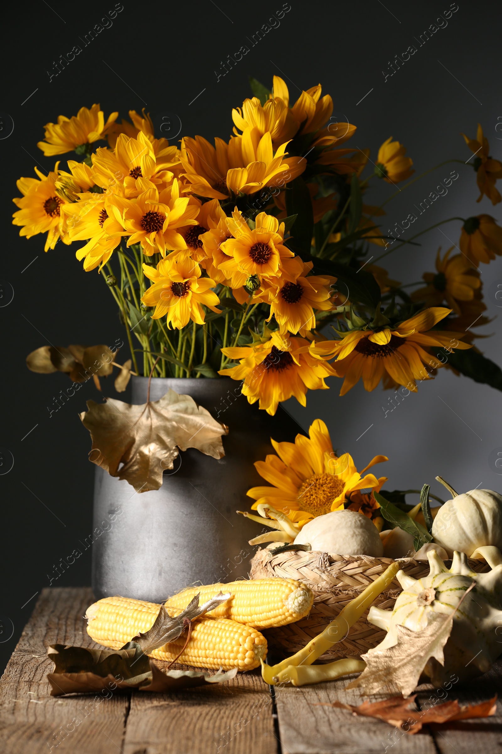 Photo of Beautiful autumn bouquet, small pumpkins and corn cobs on wooden table against dark grey background