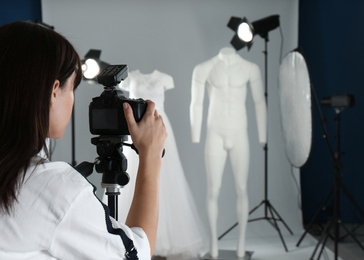 Photo of Professional photographer taking picture of ghost mannequins with stylish clothes in photo studio