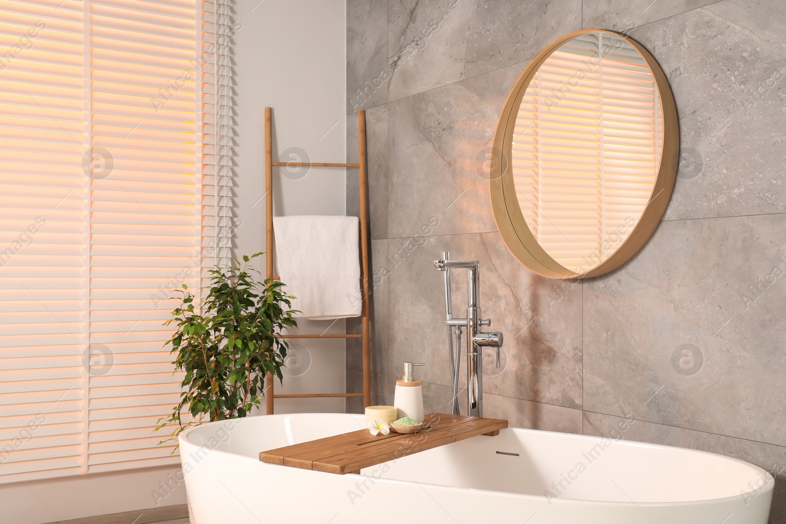 Photo of Stylish bathroom interior with ceramic tub, spa products and mirror