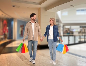 Image of Happy couple with shopping bags walking in mall
