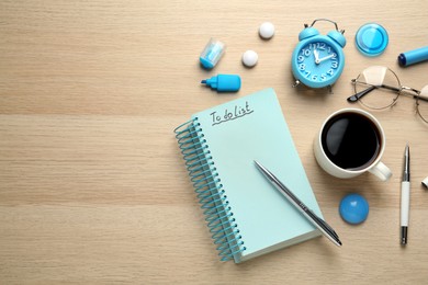 Flat lay composition with unfilled To Do list and cup of coffee on wooden table. Space for text