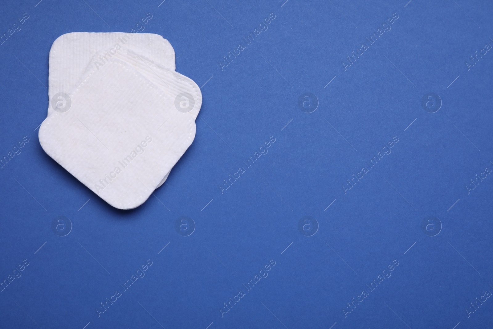 Photo of Cotton pads on blue background, flat lay. Space for text